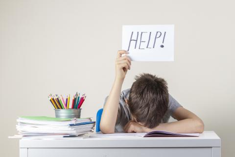 Kind hält Schild "Help" hoch